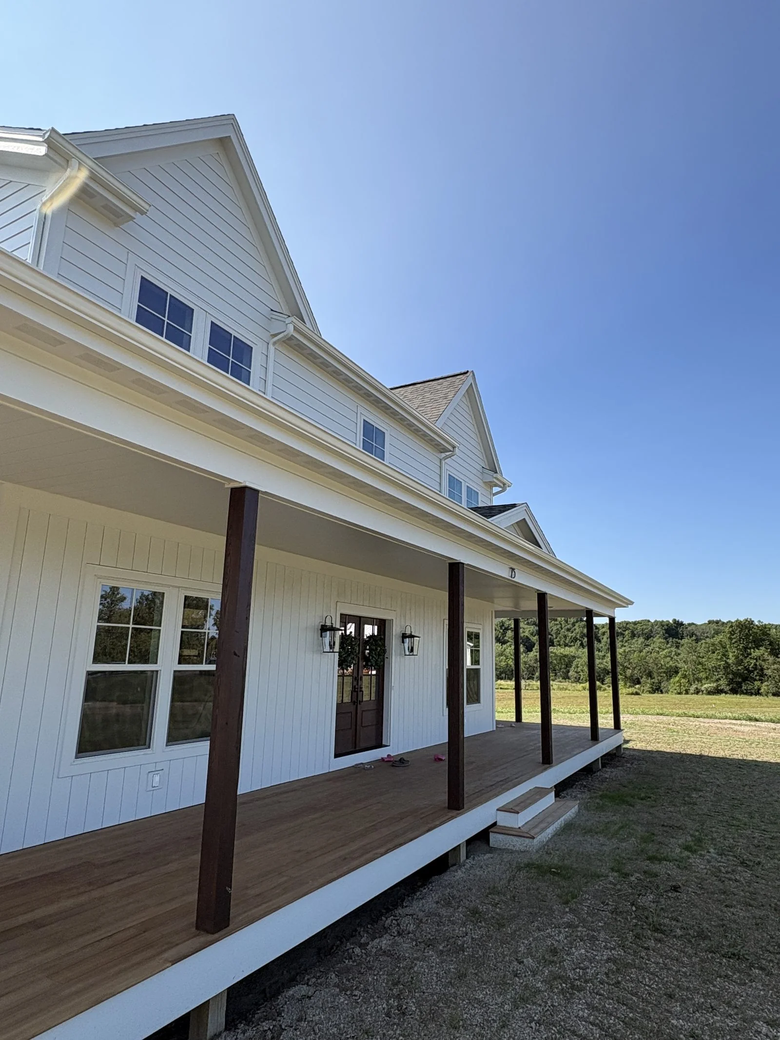 White farmhouse with a wraparound covered porch and new siding